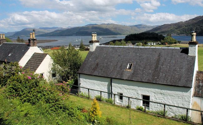 The rear garden at Bruaich Cottage, Lochcarron, slopes upwards steeply but there is a level, grassy area at the foot of the slope.